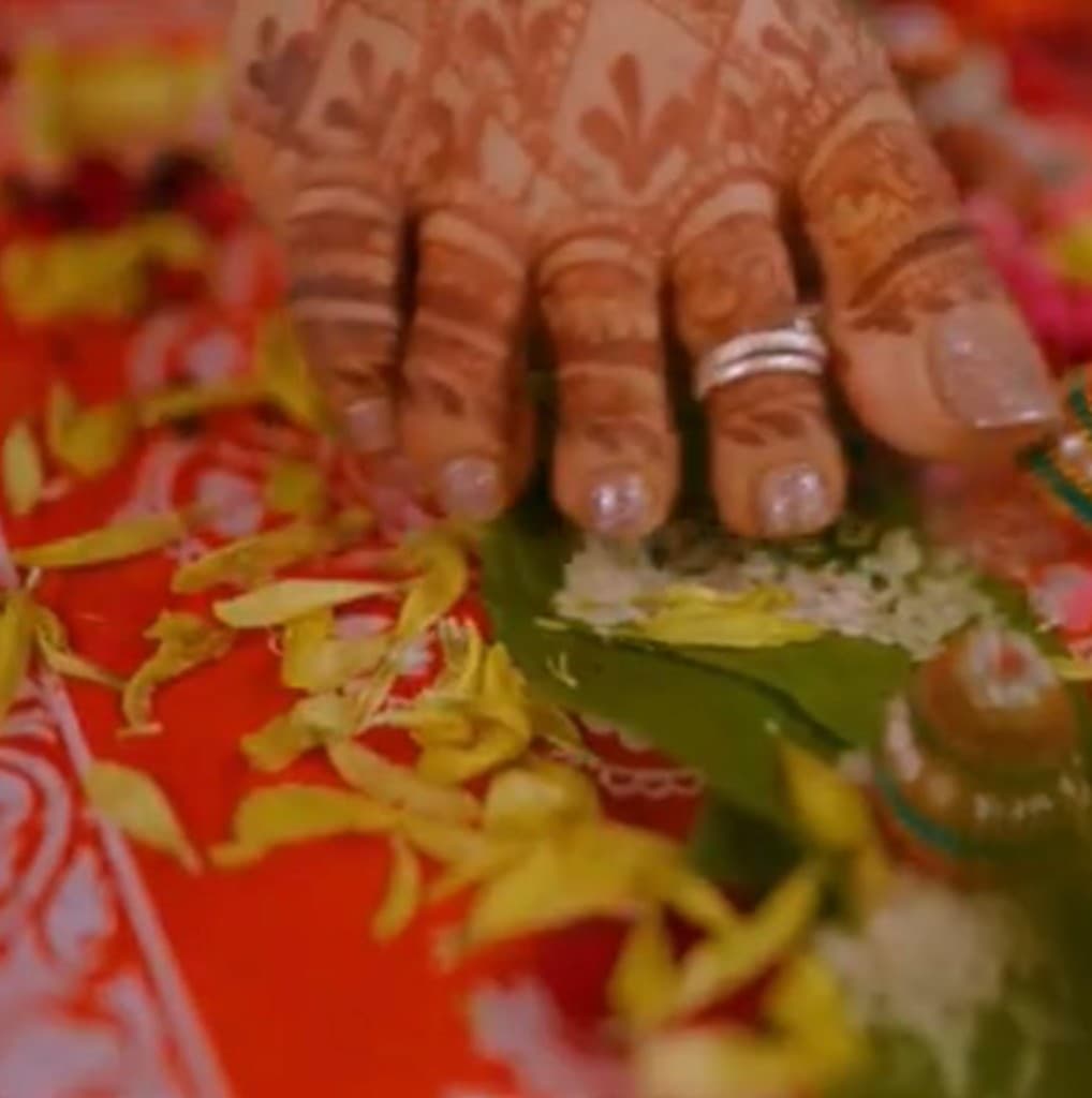 Henna on a bride’s foot stepping onto a leaf in a wedding ritual